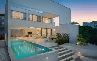 Luxurious modern house with outdoor pool and contemporary architecture at dusk.