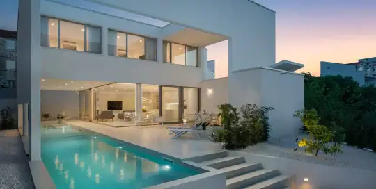Luxurious modern house with outdoor pool and contemporary architecture at dusk.