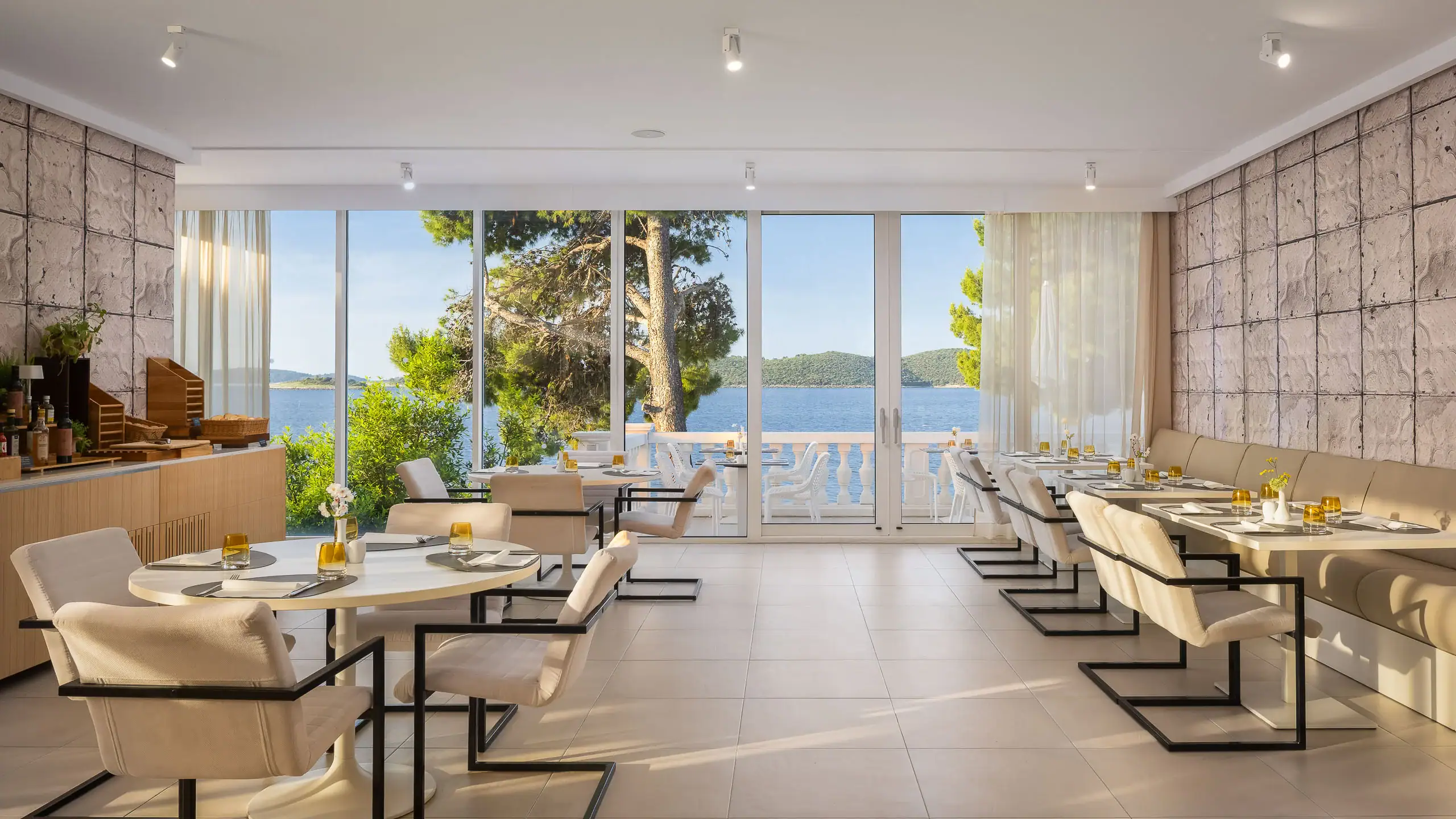Elegant dining area with large windows overlooking the sea and lush greenery.