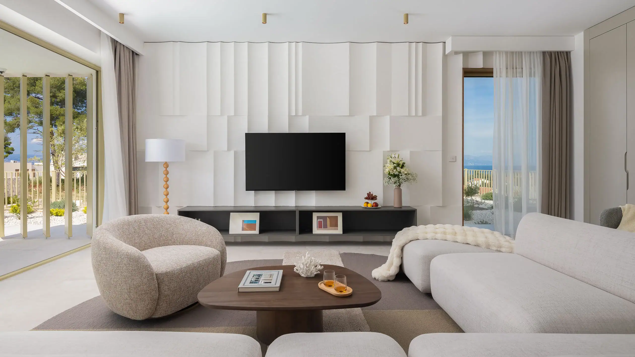 Elegant living room with white furniture, large windows, and ocean view.